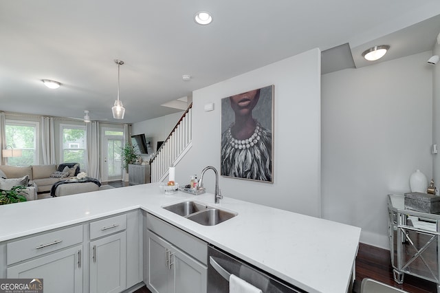 kitchen featuring pendant lighting, sink, kitchen peninsula, dark wood-type flooring, and dishwasher