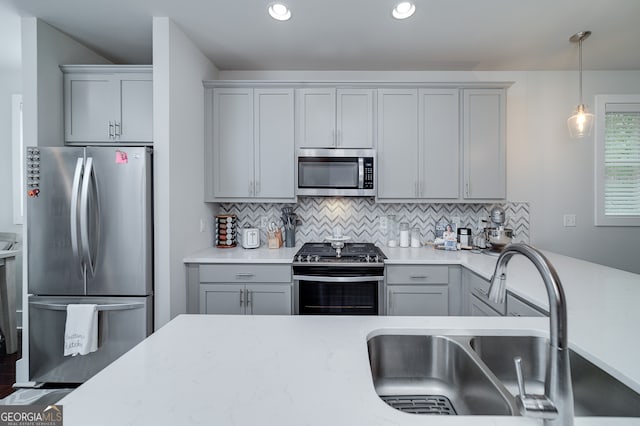 kitchen with pendant lighting, sink, backsplash, gray cabinets, and appliances with stainless steel finishes