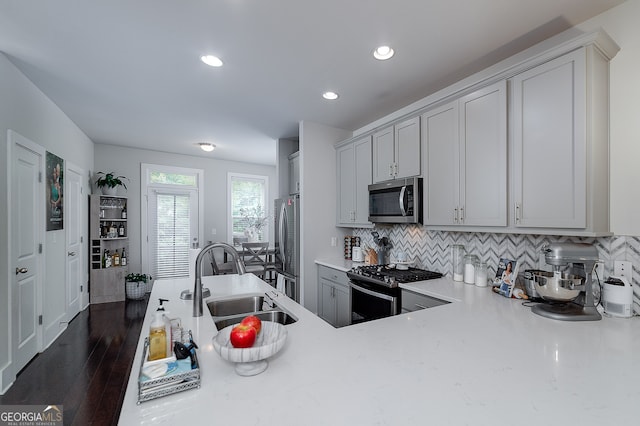 kitchen with tasteful backsplash, gray cabinetry, dark wood-type flooring, sink, and appliances with stainless steel finishes