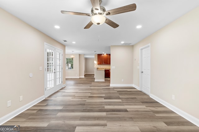 unfurnished living room featuring light wood-type flooring, ceiling fan, and french doors