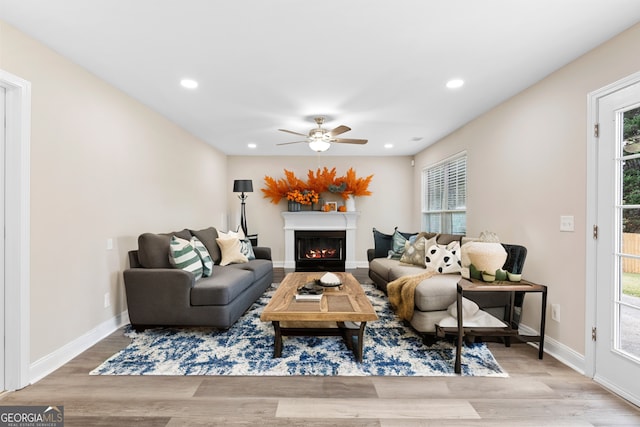 living room featuring light wood-type flooring, ceiling fan, and a healthy amount of sunlight