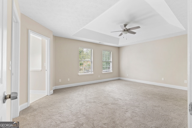 carpeted empty room featuring a textured ceiling, a tray ceiling, and ceiling fan