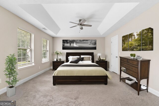 carpeted bedroom featuring ceiling fan and a tray ceiling