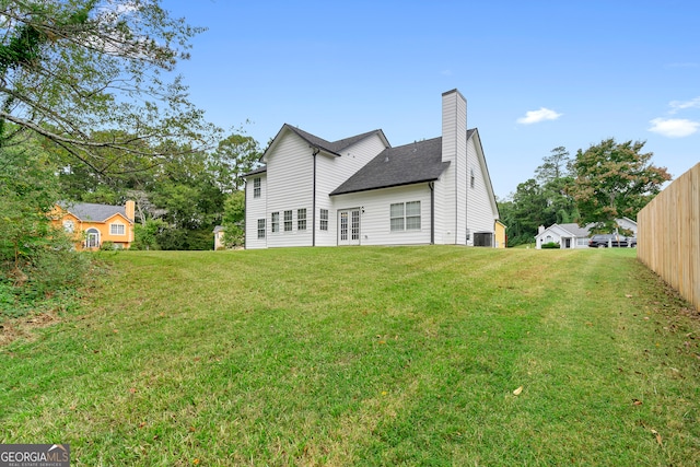 back of house with central air condition unit and a yard