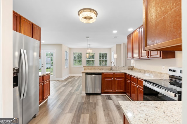 kitchen featuring pendant lighting, light wood-type flooring, sink, kitchen peninsula, and appliances with stainless steel finishes