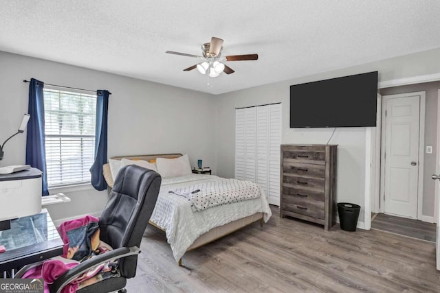 bedroom with a textured ceiling, ceiling fan, a closet, and hardwood / wood-style flooring