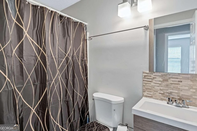 bathroom featuring a textured ceiling, backsplash, walk in shower, vanity, and toilet