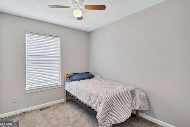 bedroom featuring ceiling fan, light colored carpet, and a textured ceiling