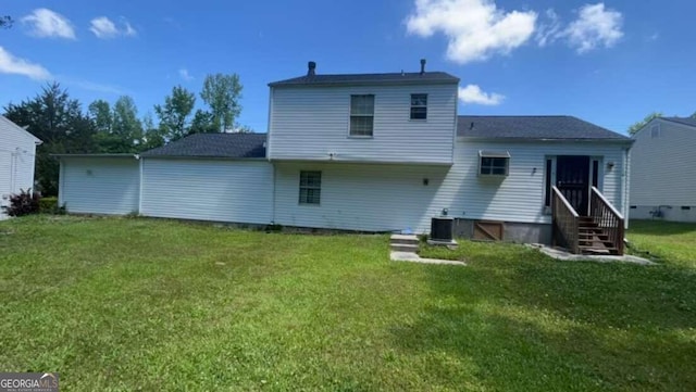 back of property featuring central air condition unit and a yard