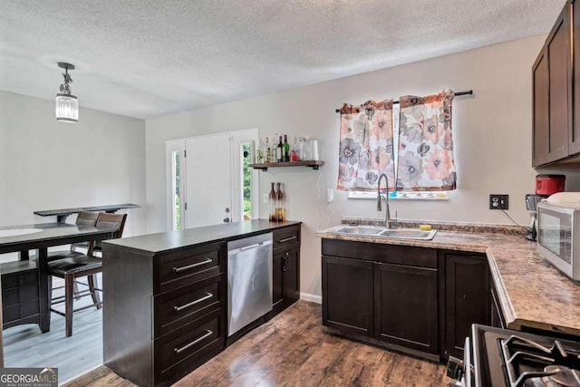 kitchen with pendant lighting, a textured ceiling, sink, appliances with stainless steel finishes, and hardwood / wood-style floors