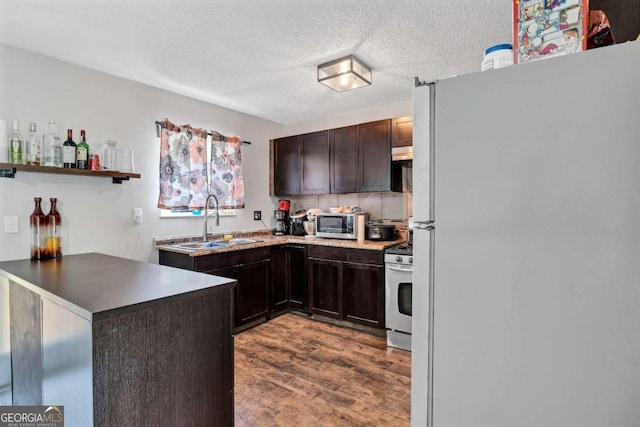 kitchen featuring sink, kitchen peninsula, appliances with stainless steel finishes, dark brown cabinetry, and hardwood / wood-style floors