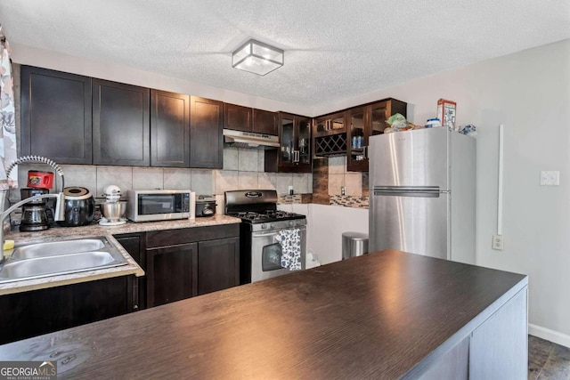 kitchen with dark brown cabinetry, sink, a textured ceiling, backsplash, and stainless steel appliances