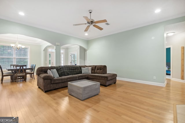 living room featuring ceiling fan with notable chandelier, light hardwood / wood-style floors, and crown molding