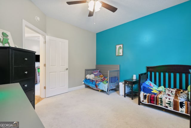 bedroom featuring ceiling fan, a textured ceiling, and light carpet