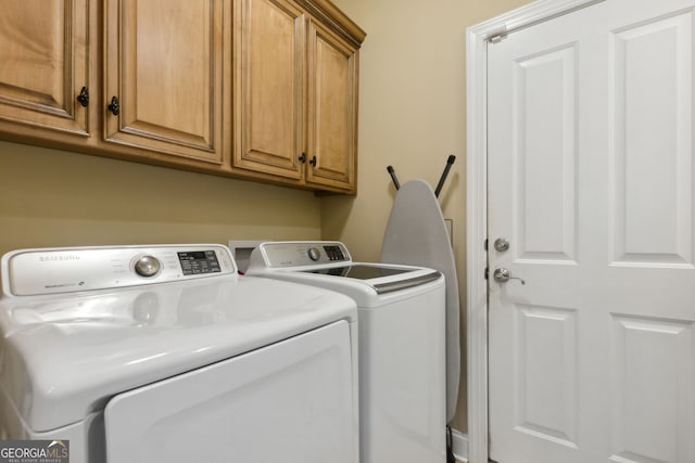 clothes washing area featuring washer and dryer and cabinets