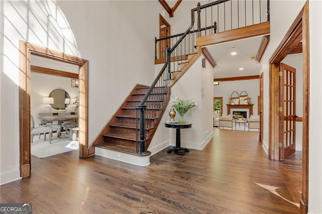 stairway featuring a towering ceiling and wood-type flooring