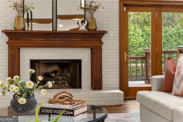 sitting room with a fireplace, brick wall, and hardwood / wood-style flooring