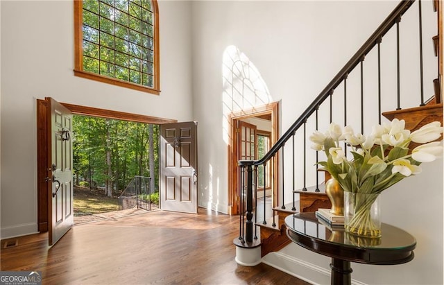 entryway with wood-type flooring and a towering ceiling