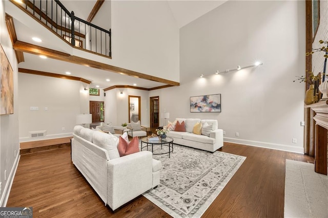 living room with a towering ceiling, crown molding, dark wood-type flooring, and a fireplace