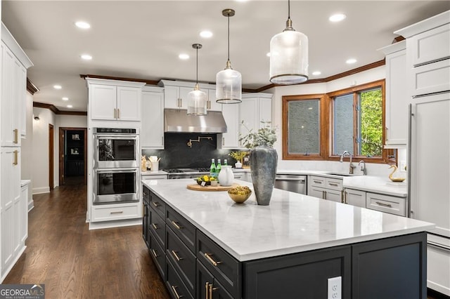 kitchen featuring a kitchen island, dark wood-type flooring, sink, hanging light fixtures, and appliances with stainless steel finishes