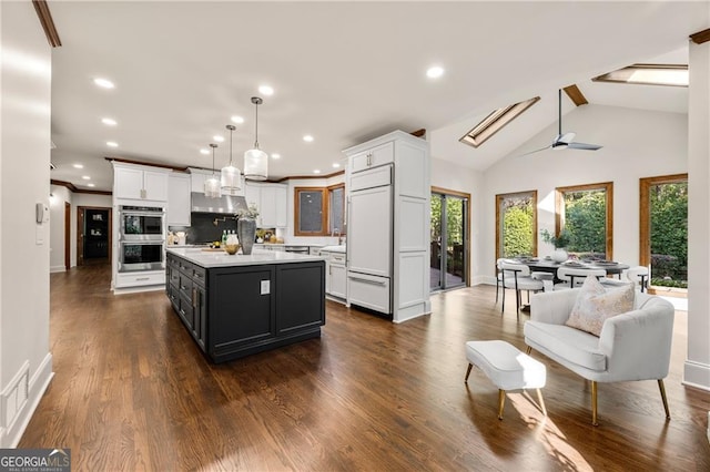 kitchen with hanging light fixtures, white cabinetry, a center island, and paneled refrigerator