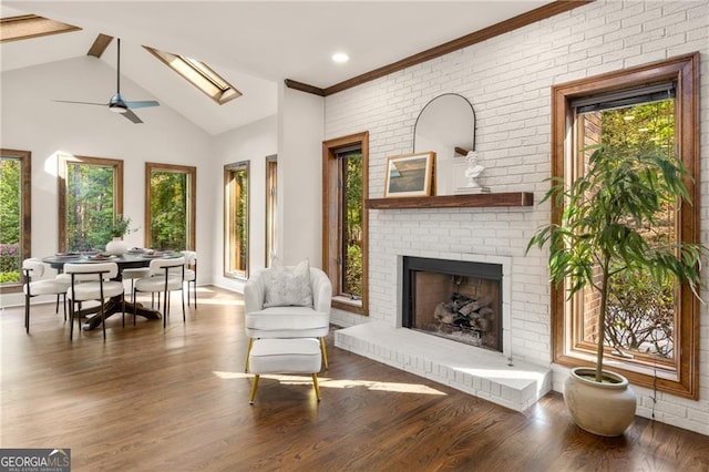 sitting room with a brick fireplace, ornamental molding, a skylight, and hardwood / wood-style floors