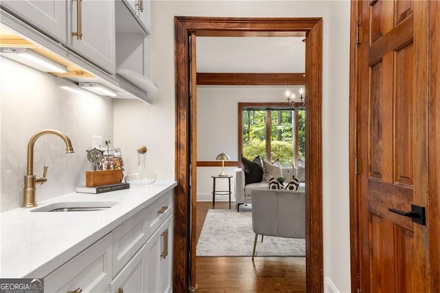 interior space with white cabinets, light stone countertops, sink, and dark hardwood / wood-style flooring