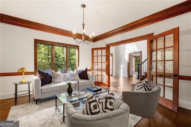 living room featuring french doors, dark hardwood / wood-style floors, ornamental molding, and a chandelier