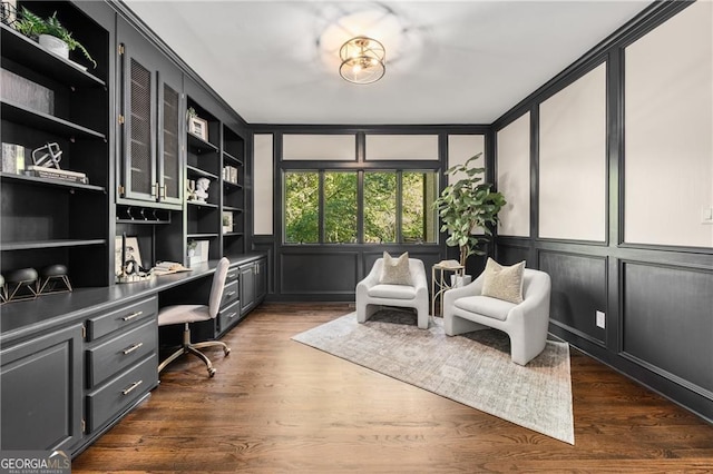 home office featuring built in shelves, built in desk, and dark wood-type flooring