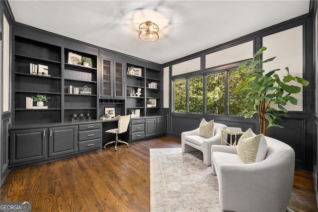 office space featuring built in shelves, built in desk, and dark hardwood / wood-style floors