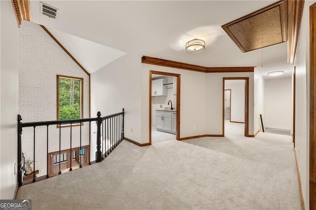 hall with light carpet, sink, and vaulted ceiling