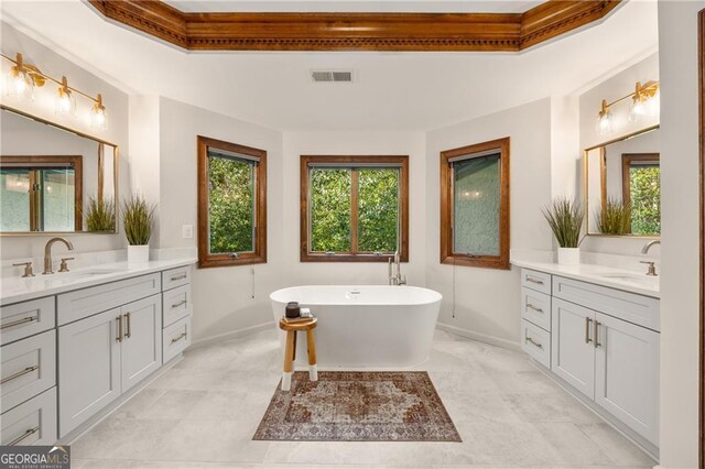 bathroom with tile patterned flooring, a tray ceiling, a washtub, and vanity