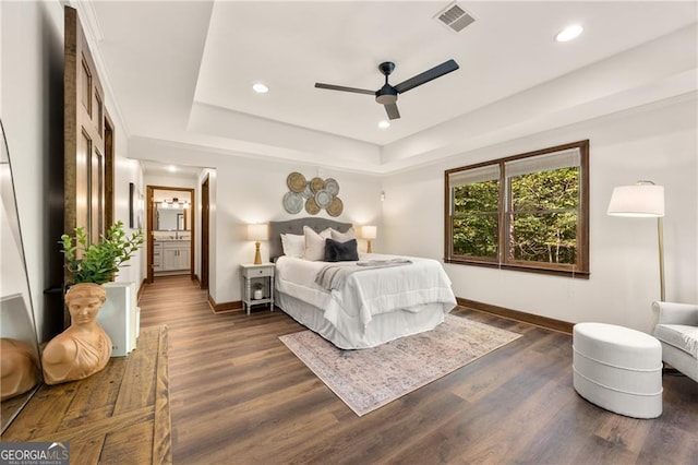 bedroom with ceiling fan, dark wood-type flooring, and a tray ceiling