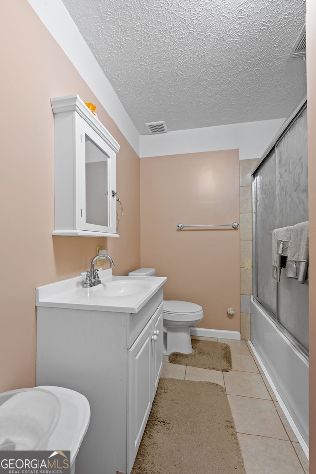 full bathroom with tile patterned flooring, a textured ceiling, vanity, enclosed tub / shower combo, and toilet