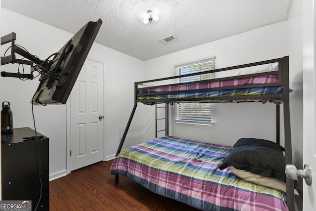 bedroom with a textured ceiling and dark wood-type flooring