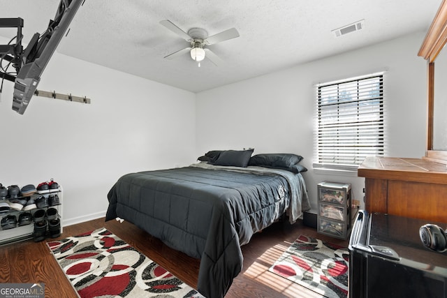 bedroom featuring ceiling fan, dark hardwood / wood-style floors, and a textured ceiling