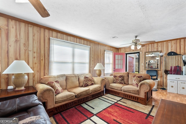 living room featuring light wood-type flooring, a textured ceiling, wood walls, and ceiling fan