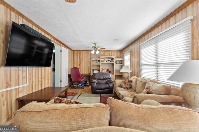 living room featuring crown molding, wooden walls, ceiling fan, and hardwood / wood-style flooring