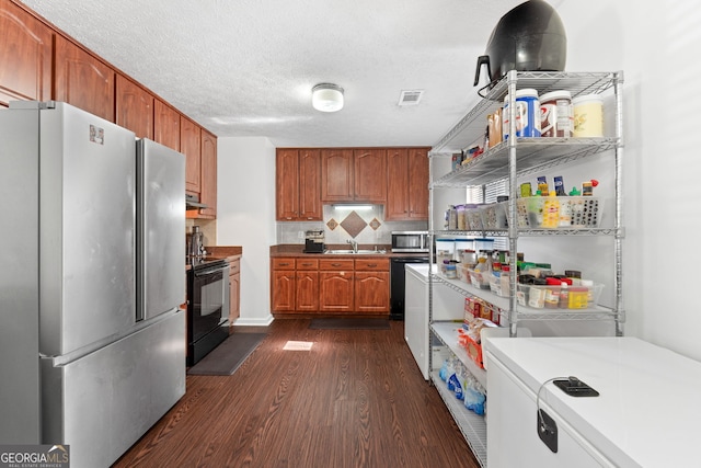 kitchen with backsplash, dark hardwood / wood-style flooring, stainless steel appliances, a textured ceiling, and sink