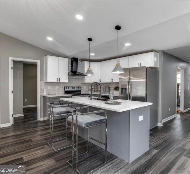 kitchen featuring stainless steel electric range oven, white cabinetry, wall chimney range hood, and an island with sink