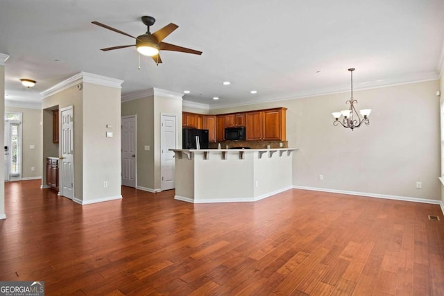 unfurnished living room with ornamental molding, ceiling fan with notable chandelier, and dark wood-type flooring