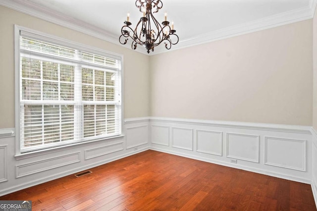 empty room featuring wood-type flooring, crown molding, and an inviting chandelier