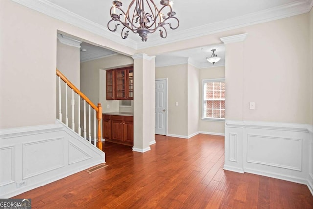 interior space featuring ornamental molding, a chandelier, dark wood-type flooring, and ornate columns