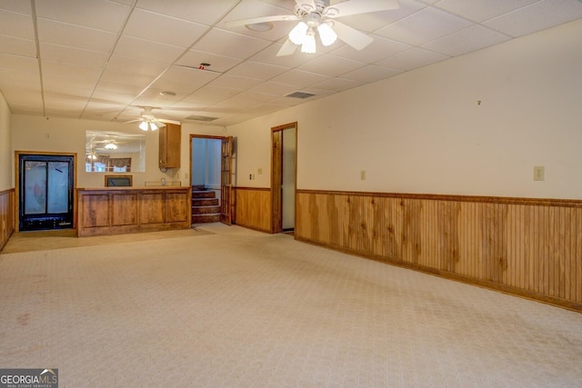 carpeted empty room with ceiling fan and a drop ceiling