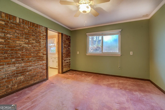 carpeted spare room featuring ceiling fan, crown molding, and brick wall