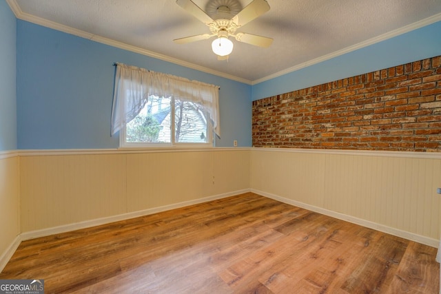 spare room with ornamental molding, brick wall, a textured ceiling, ceiling fan, and hardwood / wood-style floors