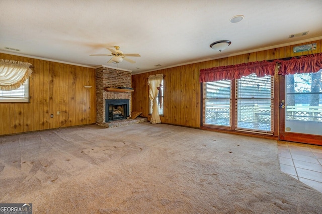 unfurnished living room with carpet, ceiling fan, crown molding, and a fireplace