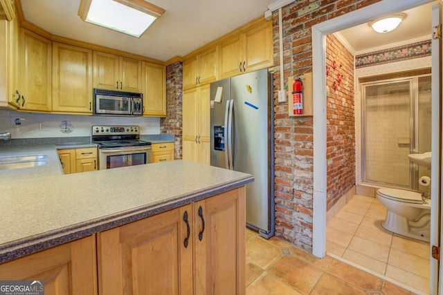 kitchen featuring brick wall, light tile patterned floors, crown molding, and appliances with stainless steel finishes