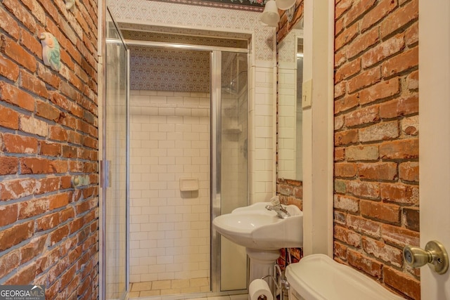 bathroom featuring toilet, walk in shower, and brick wall