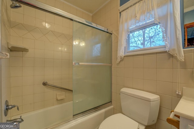 full bathroom with combined bath / shower with glass door, ornamental molding, vanity, tile walls, and toilet